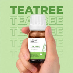 Hand holding a bottle of Lavera Tea Tree essential oil against a green background with 'Tea Tree' text.